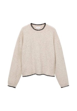 Svetlo bež pulover z dolgimi rokavi. Ima črn valovit obrobni rob na vratu in robu. Narejen iz mehkega, teksturnega blaga. Skrajšana zasnova.