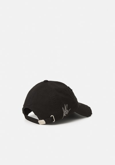 Black cotton baseball cap with a distressed design, adjustable strap, and metallic buckle. Features a signature in white on the side.