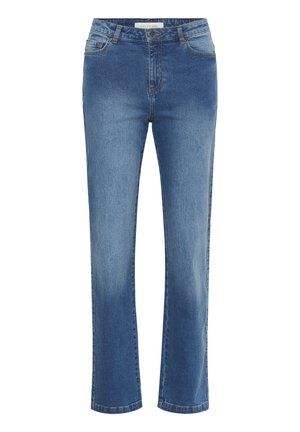 Frau mit lockigem Haar, die ein marineblau-weiß gestreiftes kurzärmeliges Oberteil, blaue gerade Jeans und schwarze Ballettschuhe trägt und mit einer Hand in der Hüfte steht.