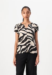 Kortærmet top i beige og sort zebrastribet mønster, med V-hals og afslappet pasform. Glat tekstur og kontrasterende grafisk mønster.