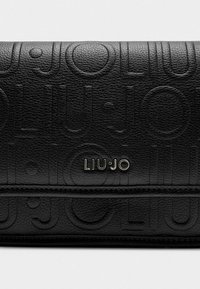 Cartera de cuero negro con el logo en relieve "LIU·JO" y una textura suave, que presenta un diseño horizontal y detalles de costura sutiles.