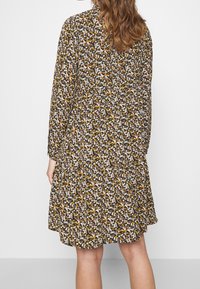 Floral dress featuring a dark background with small white and yellow flowers, long sleeves, and a tiered hemline. Lightweight fabric.