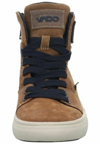 Braune Wildleder-Hochschnittsneaker mit marineblauen Schnürsenkeln, gepolstertem Kragen und Gummisohle. Mit "VADO"-Branding auf der Zunge und seitlichen Akzenten.