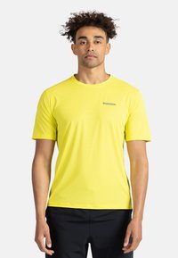 Ljusgul kortärmad träningsskjorta i lätt tyg. Har en rund halsringning och en subtil Rossignol-logotyp på bröstet.