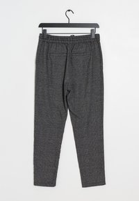 Pantalon gris à motif avec une ceinture élastique, deux poches arrière et une coupe fuselée. Le tissu présente une finition texturée.