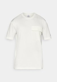 Camiseta blanca de manga corta hecha de algodón, con un bolsillo en el pecho con solapa, escote redondeado y una marca discreta en la manga.