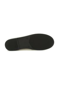 Schwarze Gummisohle mit strukturiertem Grip, minimalistisches Design und eine glatte weiße Oberseite. Besondere Form mit abgerundetem Zeh und flacher Silhouette.