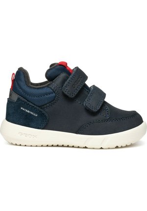 Granatowe sneakersy z zapięciem na rzepy, wodoodpornego materiału, z zamszowymi akcentami i białą gumową podeszwą. Posiadają czerwoną metkę na pięcie.