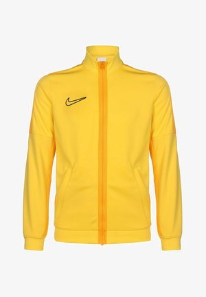 Giacca da track Nike gialla con colletto alto, zip intera, logo nero sul petto e tasche laterali. Tessuto liscio con un design aderente.