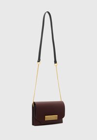 Bordeaux læder crossbody taske med en guldtonet rektangulær hardware detalje. Har en sort justerbar rem og en glat overflade.