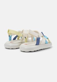 Lightweight sandals in cream with multicolored straps (yellow, blue, navy) and a cushioned sole, featuring textured rubber bottoms.