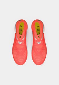 Lyse koralfarvede fodboldstøvler med en struktureret overdel, med sølvaccenter og en mønstret sål. Snørebånd og polstret krave inkluderet.