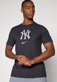 Dark grey cotton t-shirt featuring a large white NY logo and small Nike swoosh, short sleeves, crew neck, and a relaxed fit.