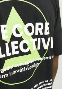 Black cotton t-shirt featuring a large green triangle logo and white text with a modern font, emphasizing "The Core Collective" and design elements.