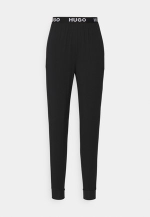 Black pants with an elastic waistband featuring the logo "HUGO." The design is simple with tapered legs and cuffs. Soft, stretchy material.