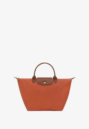 Orange nylon tote bag with brown leather accents, rounded handles, and a snap closure. Features a front pocket and a zippered top.