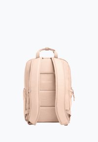 Mochila beige con correas ajustables, dos bolsillos laterales y cierre de cremallera. Cuenta con un panel trasero acolchado y un logo impreso en la parte frontal.