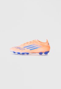 Scarpino da calcio arancione brillante con accenti blu, caratterizzato da un design leggero, superficie texturizzata e silhouette bassa per l'agilità.