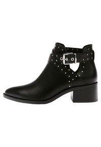 Botines negros de cuero con punta afilada, correa con tachuelas y hebilla plateada, que presentan un tacón bloque medio.