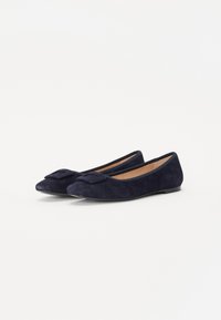 Ballerines en daim bleu marine avec un bout pointu et un accent en nœud sur le dessus. Le design présente une semelle basse et flexible ainsi qu'une doublure lisse.