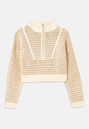 Suéter corto de un beige claro con cuello tipo chimenea con cremallera, que presenta un patrón texturizado y puños y dobladillo acanalados. Combina materiales de punto y tejido.
