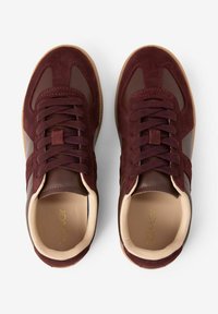 Baskets bordeaux en mélange de daim et de cuir, avec bout arrondi, design à lacets et doublure intérieure beige. Semelle en caoutchouc avec grip texturé.