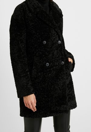 Sort, fluffy dobbeltbrystet frakke med en tekstureret overflade, der har store knapper, indsnittede klipper og sidelommer.