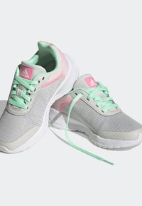  Scarpe da ginnastica grigie con tessuto a rete, con accenti rosa e menta. I lacci sono verde menta, con una suola bianca spessa e dettagli del logo.