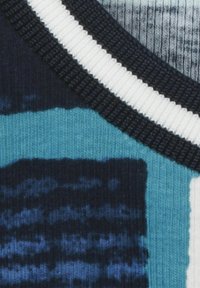 Close-up van stof met gebreide patronen in blauw, zwart, wit engrijs, met duidelijke ribbel- en geweven texturen.