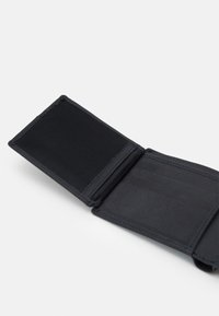 Portefeuille bifold noir en cuir texturé ; l'intérieur dispose de fentes pour cartes et d'une fenêtre pour ID en maille. Design minimaliste avec des coutures bleues.