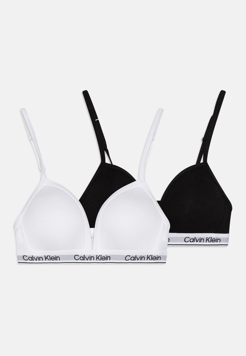 Två triangelformade behåar i vitt och svart, tillverkade av mjuk bomull, med tunna remmar och ett elastiskt band med varumärket "Calvin Klein".