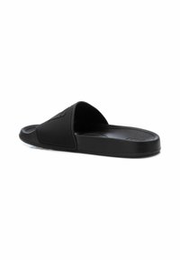 Chanclas negras con una correa texturizada, una suela plana y una plantilla suave. Diseño simple con un detalle mínimo y sin herrajes visibles.