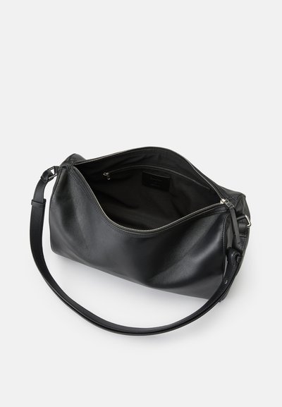 Borsa a spalla in pelle nera con una lunga tracolla regolabile e zip aperta che mostra un interno foderato in tessuto con una tasca interna con zip.
