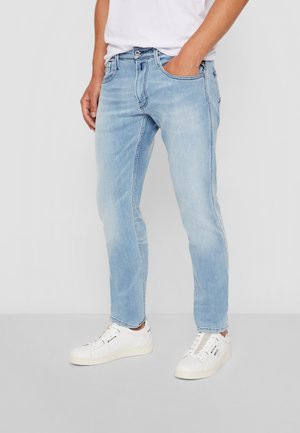 Jasnoniebieskie dżinsy o slim fit, z pięcioma kieszeniami i delikatnymi przetarciami. W połączeniu z białymi sneakersami dla uzyskania swobodnego wyglądu.