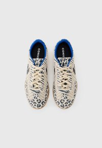Beige sneakers med blå accenter, der har leopardprint og stribede mønstre. Tekstureret sål og sort branding på indersålerne.