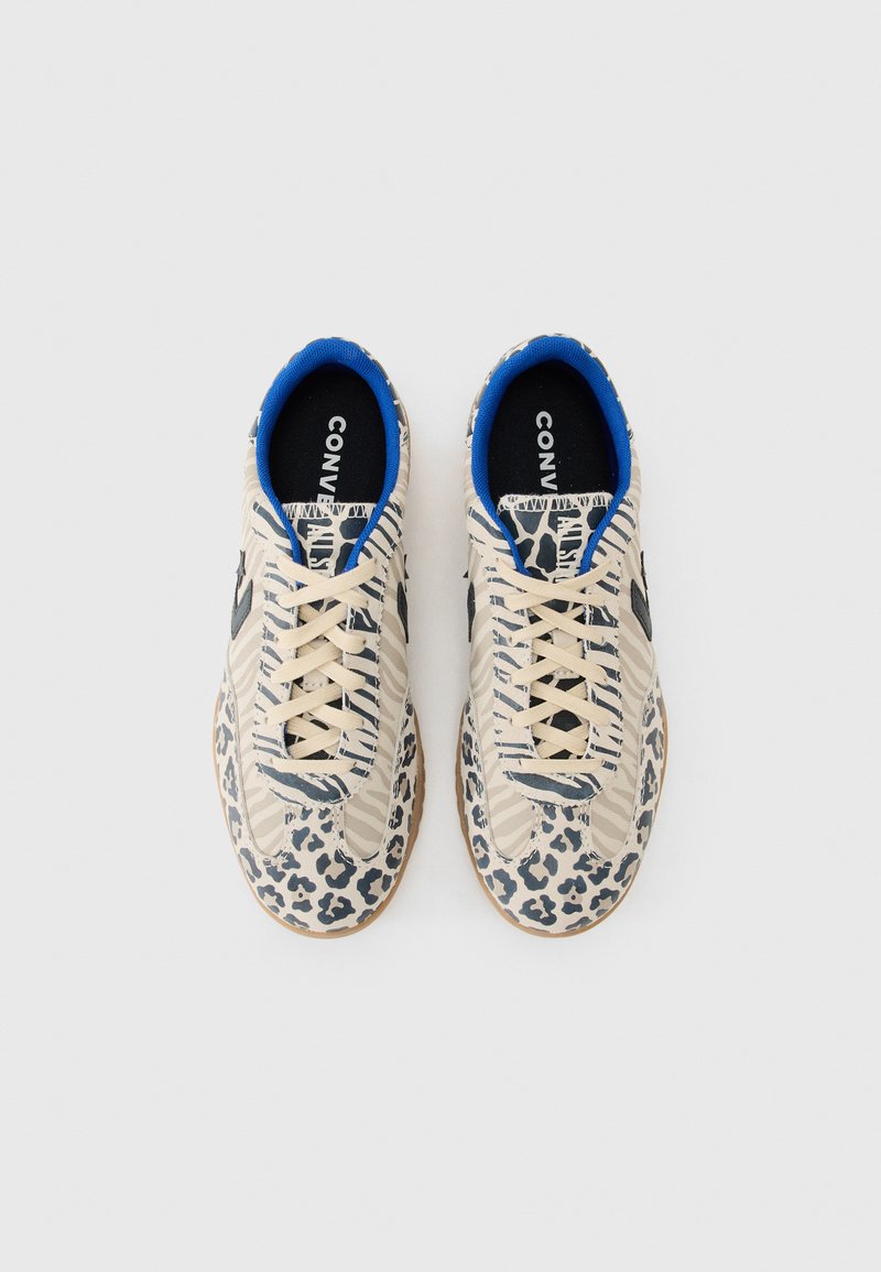 Zapatillas beige con detalles azules, que presentan un estampado de leopardo y patrones a rayas. Suela texturizada y marca negra en las plantillas.