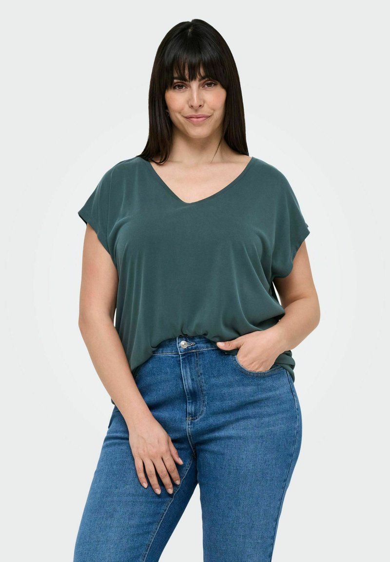 Loose-fitting, dark green V-neck t-shirt with short sleeves, paired with light blue high-waisted jeans. Smooth fabric, relaxed silhouette.