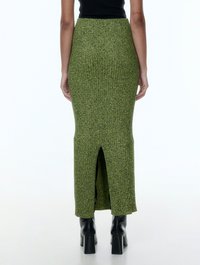 Groene geribbelde gebreide lange rok met een achterkant split, met een nauwsluitende taille en een rechte silhouet, gecombineerd met zwarte hoge laarzen.