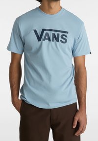 Světle modré tričko s krátkým rukávem vyrobené z bavlny, s tmavě modrým logem "VANS" přes prsa. Hladký povrch, design s kulatým výstřihem.
