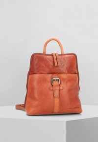 Sac à dos en cuir tan au design structuré, avec une poignée supérieure, des bretelles réglables, un détail de boucle à l'avant et une texture lisse.