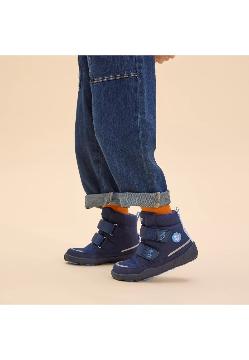 Botas altas de color azul oscuro con dos correas ajustables, suelas de goma y tejido texturizado. Incluyen acentos de color azul claro y detalles de logotipo.