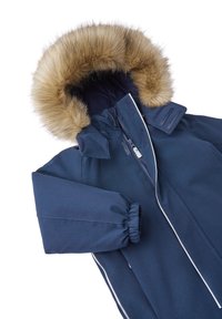 Navyblauwe jas met faux fur capuchon, ritssluiting en elastische manchetten. Kenmerkt zich door witte accentstiksels en een textured stof voor isolatie.