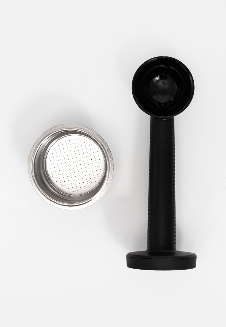 Ein schwarzer Kaffeetamper steht neben einem silbernen Metall-Kaffeefilter mit kleinen Löchern, beides auf einem weißen Hintergrund.