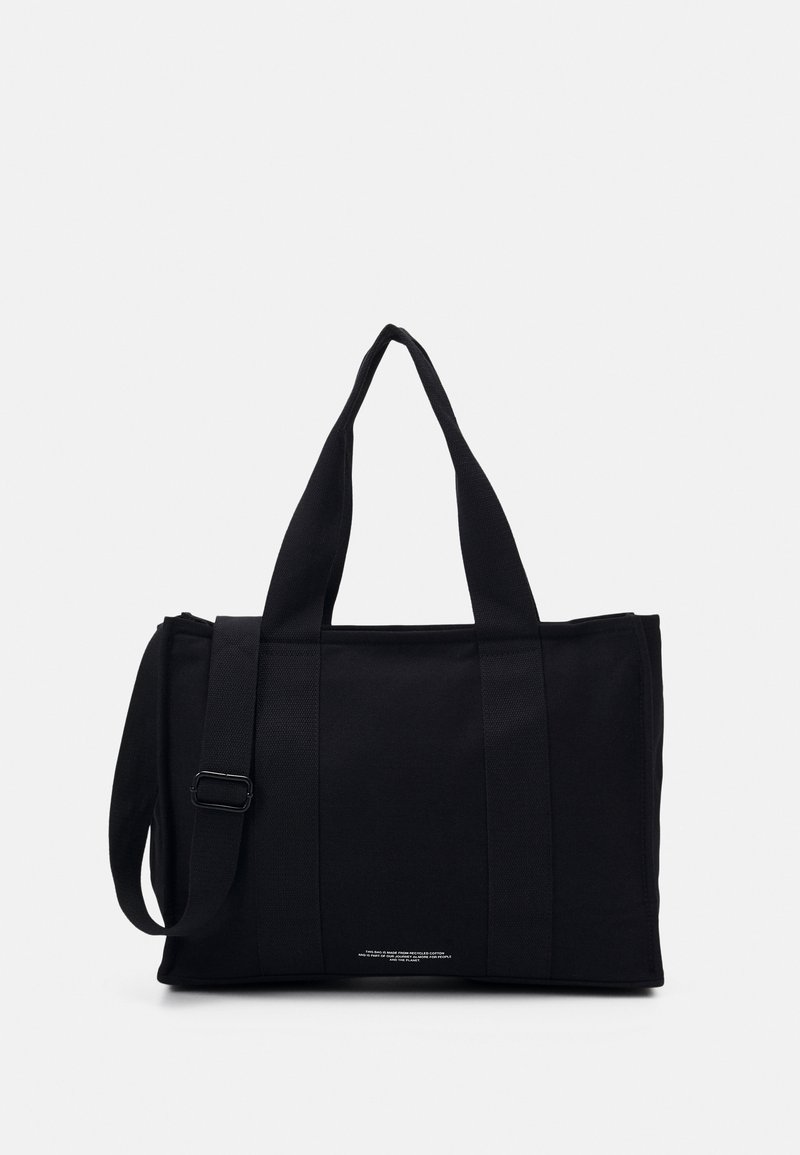 Sac cabas rectangulaire noir avec deux poignées et une bandoulière réglable sur un fond clair uni.