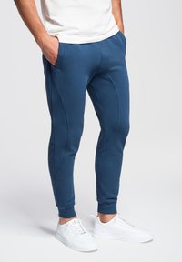 Marineblauwe sportieve joggers gemaakt van zachte stof, met een tapered fit, zijzakken en zichtbare naden voor een sportieve uitstraling.