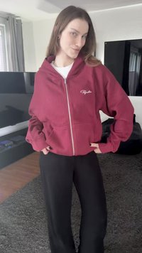 Ribbad vinröd zip-up hoodie med fickor, med en vit broderad logotyp på vänster bröst. Matchas med svarta byxor med vida ben.