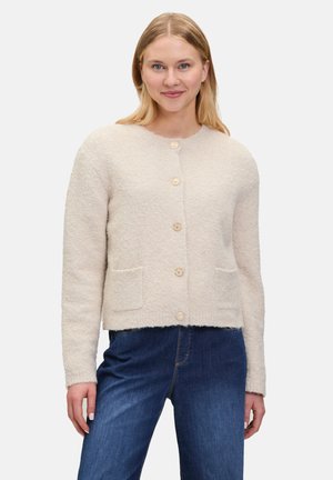 Beige villasekoitteen neuletakki, jossa on pyöreä kaula-aukko, edessä nappikiinnitys ja kaksi läpällistä taskua. Teksturoitu, keskipitkä hiha, suora istuvuus.