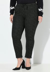 Černé pletené kalhoty s texturovaným vzorem, mají elastický pas a stahovací šňůrku. Srolemanté nohavice a slim fit.