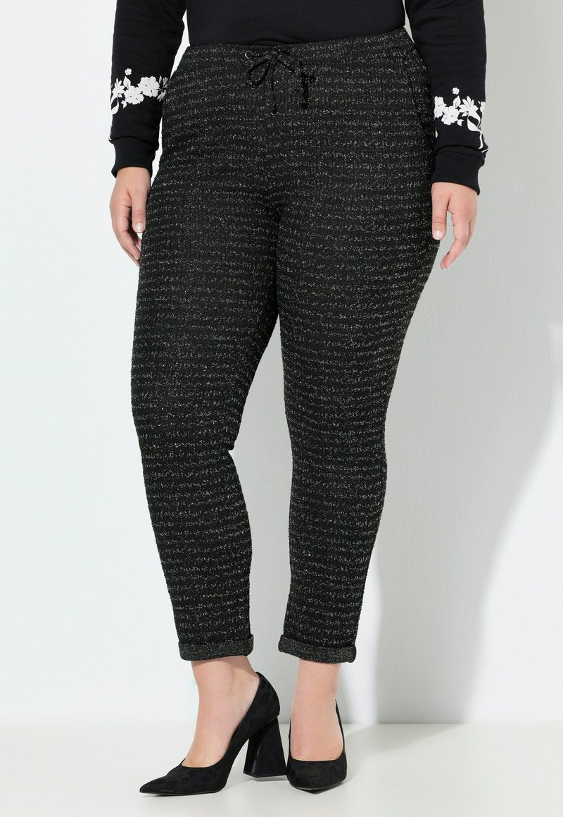 Černé pletené kalhoty s texturovaným vzorem, mají elastický pas a stahovací šňůrku. Srolemanté nohavice a slim fit.