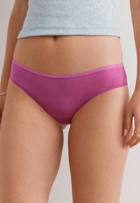 Roze naadloze ondergoed met een subtiel textuurpatroon, voorzien van een dunne elastische tailleband. Het materiaal lijkt rekbaar en zacht.